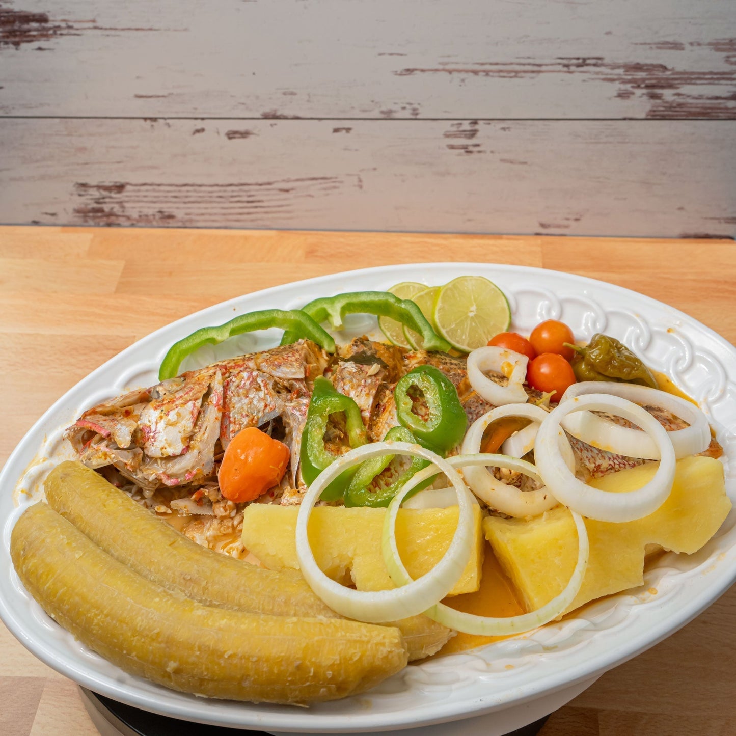 Haitian Stewed fish recipe on a white plate and wood counter top