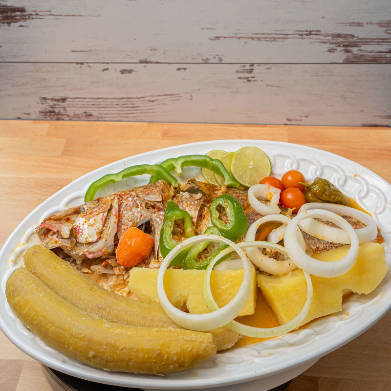 Haitian Stewed fish recipe on a white plate and wood counter top