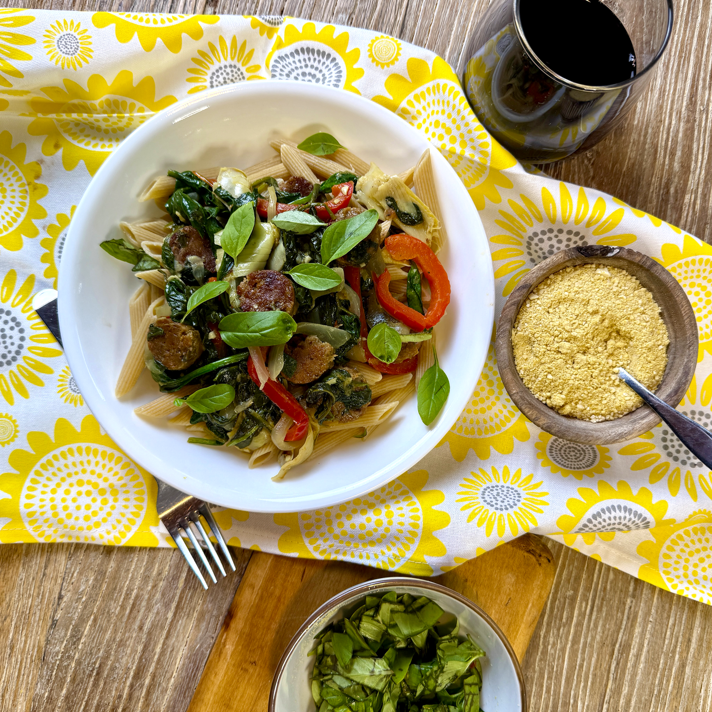 Plate of veggie pasta on a table with a yellow patterned napkin